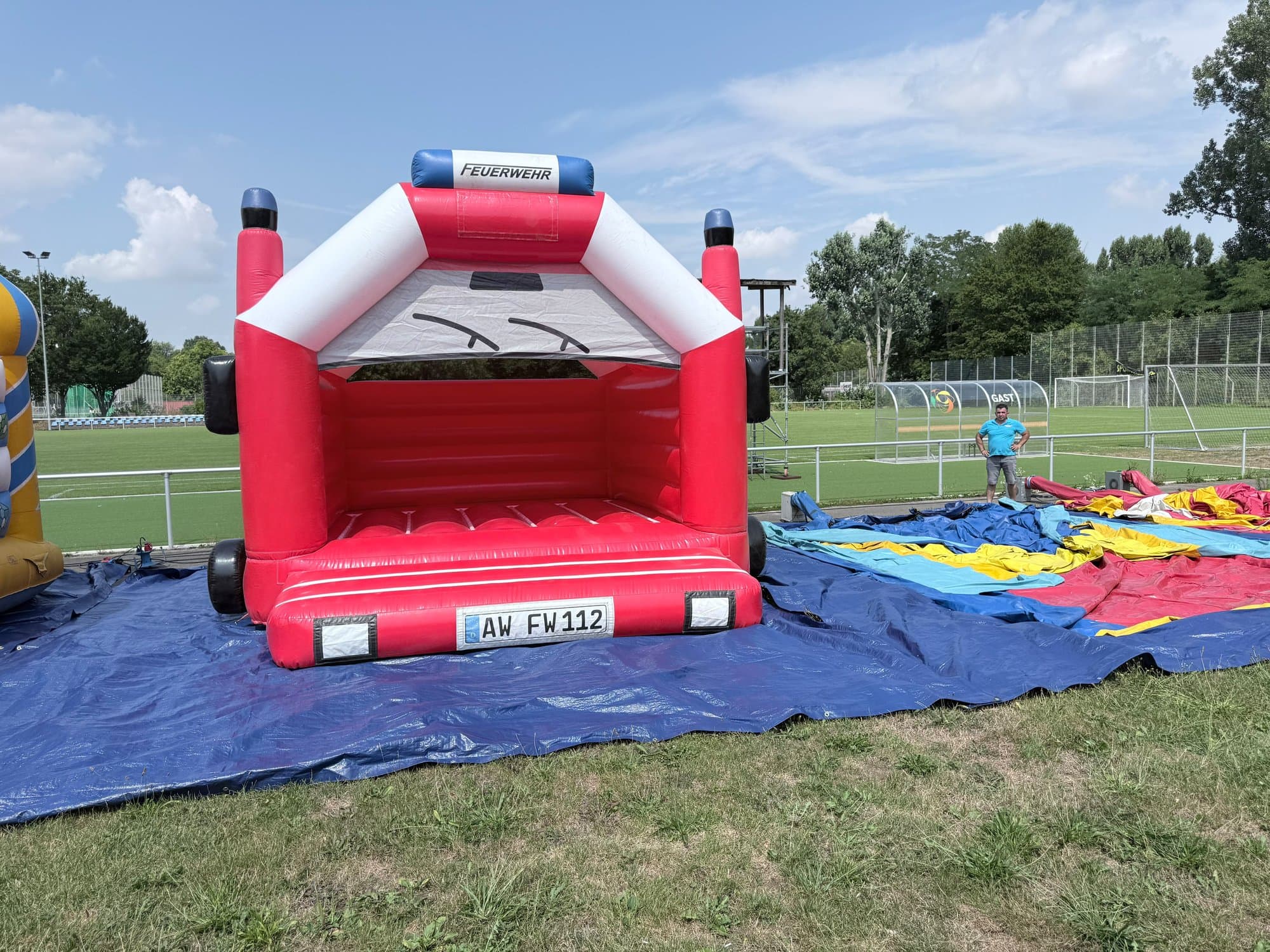 Rot-weiße Feuerwehr-Hüpfburg auf einer Plane am Sportplatz