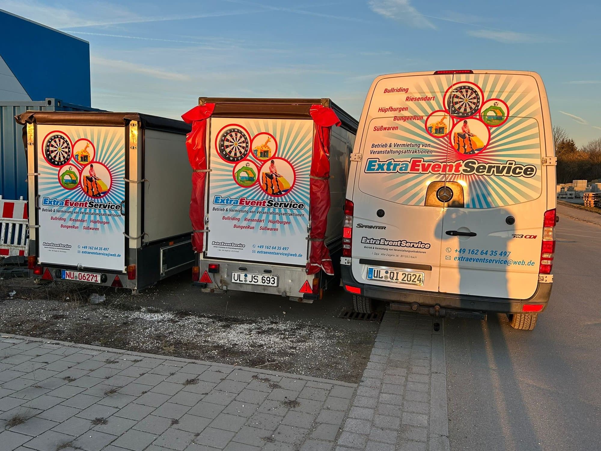 Transporter und zwei Anhänger mit ExtraEventService-Beschriftung im Abendlicht, Heckansicht